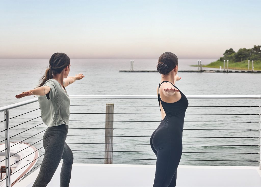 two girls doing yoga in front of the water