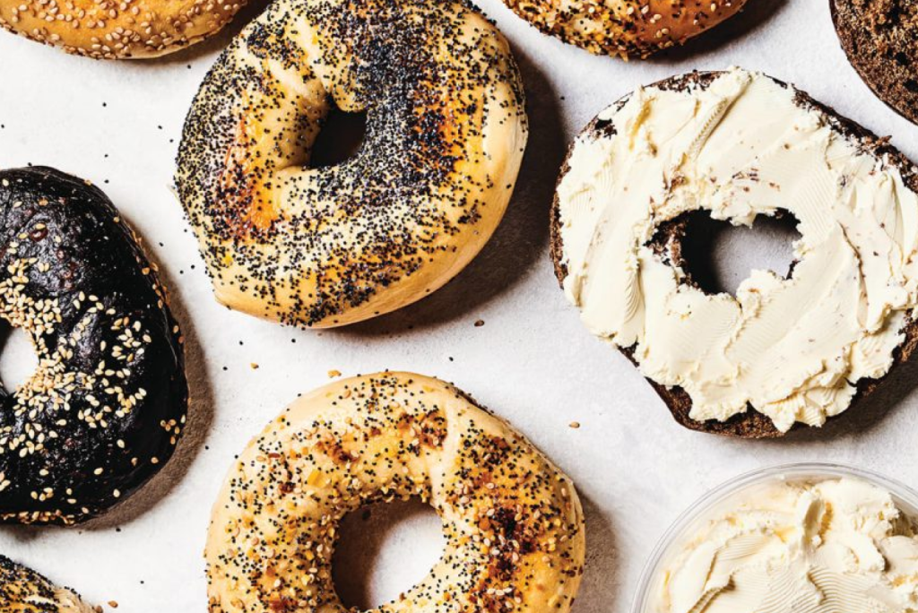 A group of bagels topped with cream cheese and black sprinkles.