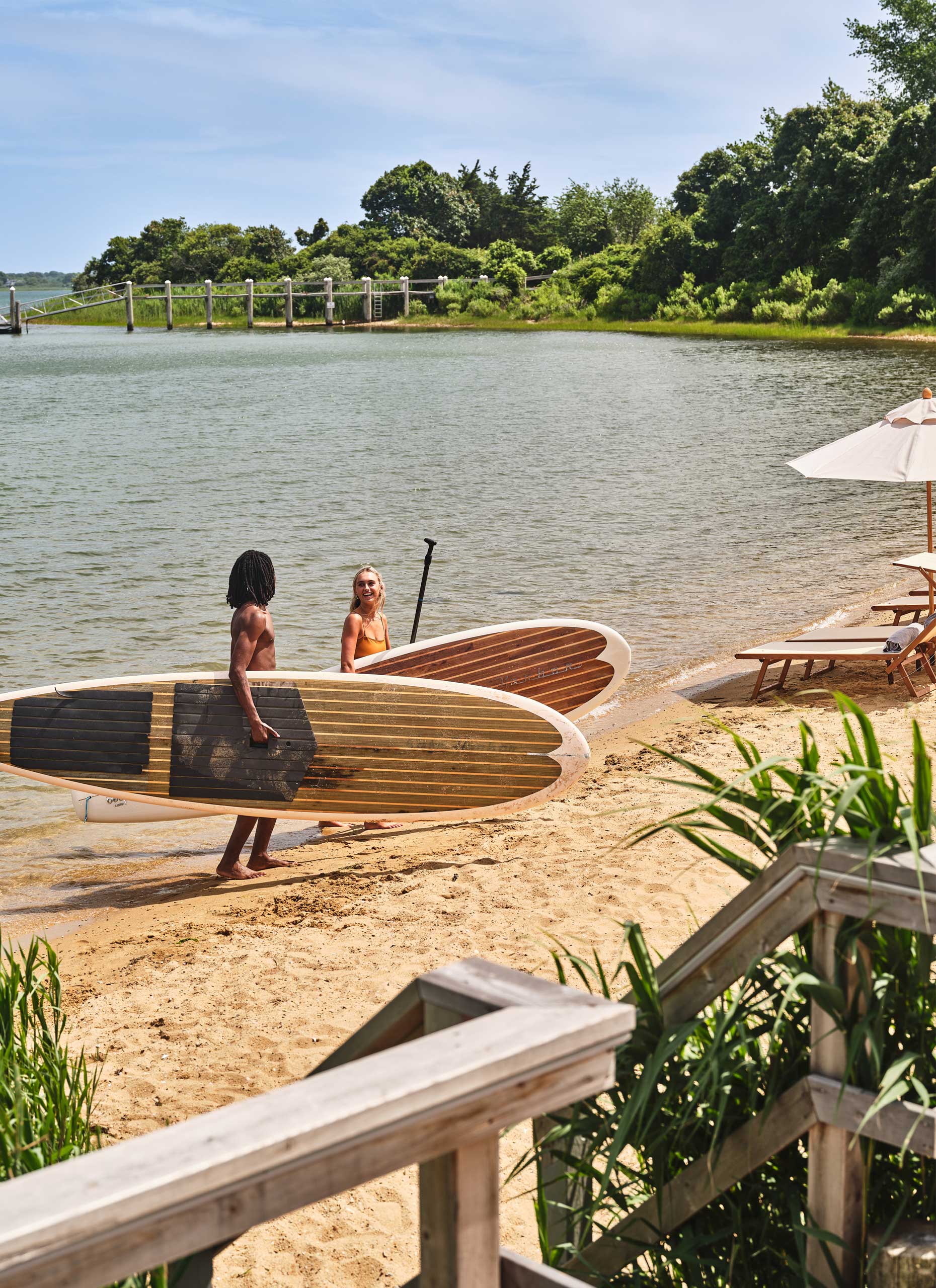 people carrying paddle boards on beach