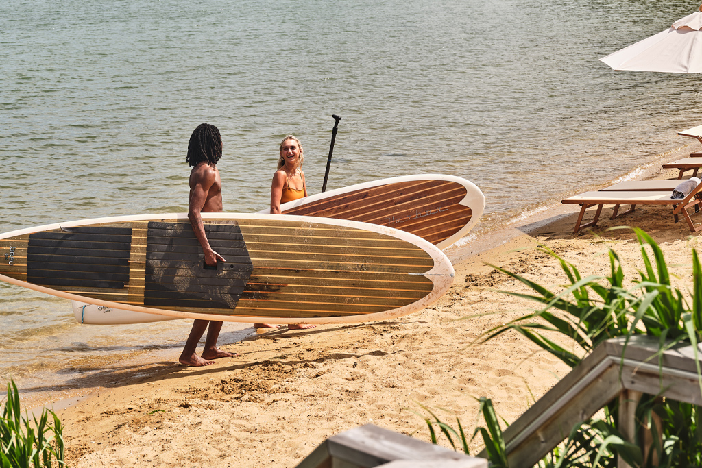 two people carrying paddle boards