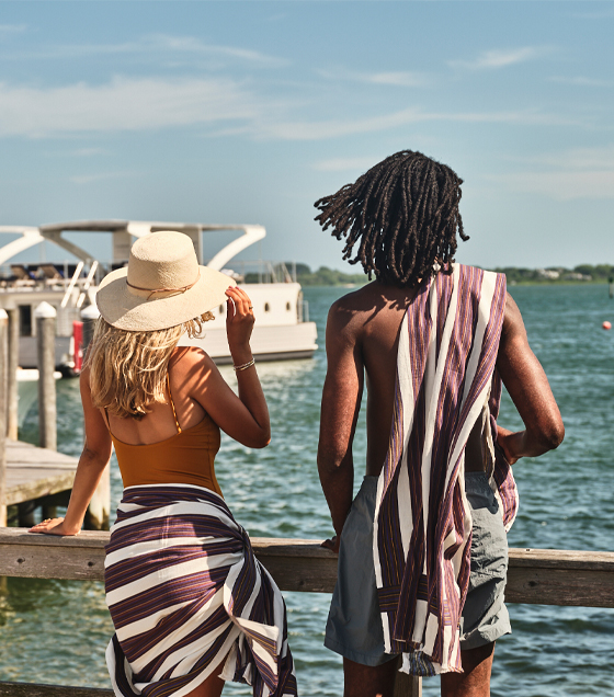 A man and woman stand on a dock, admiring the beautiful sea view.