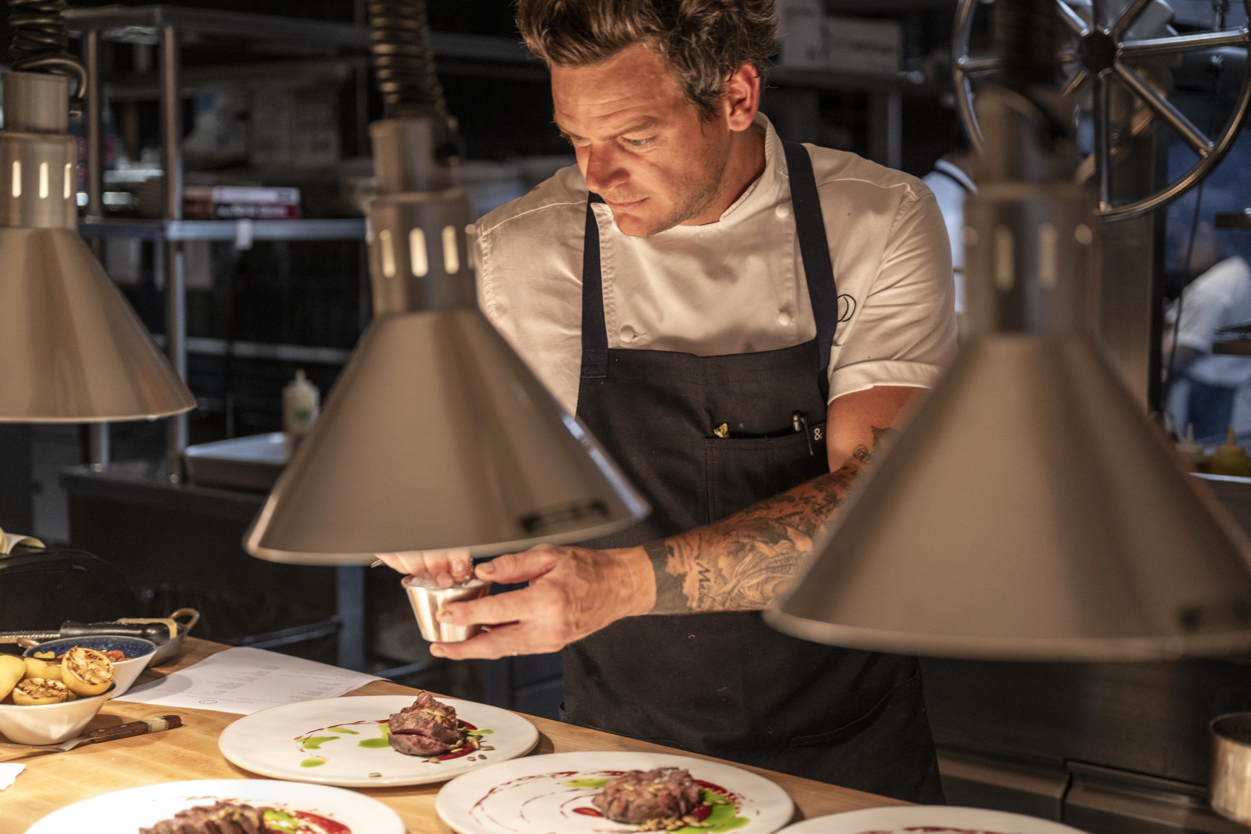 A chef garnishes the delicious dish, which is being prepared for the client.