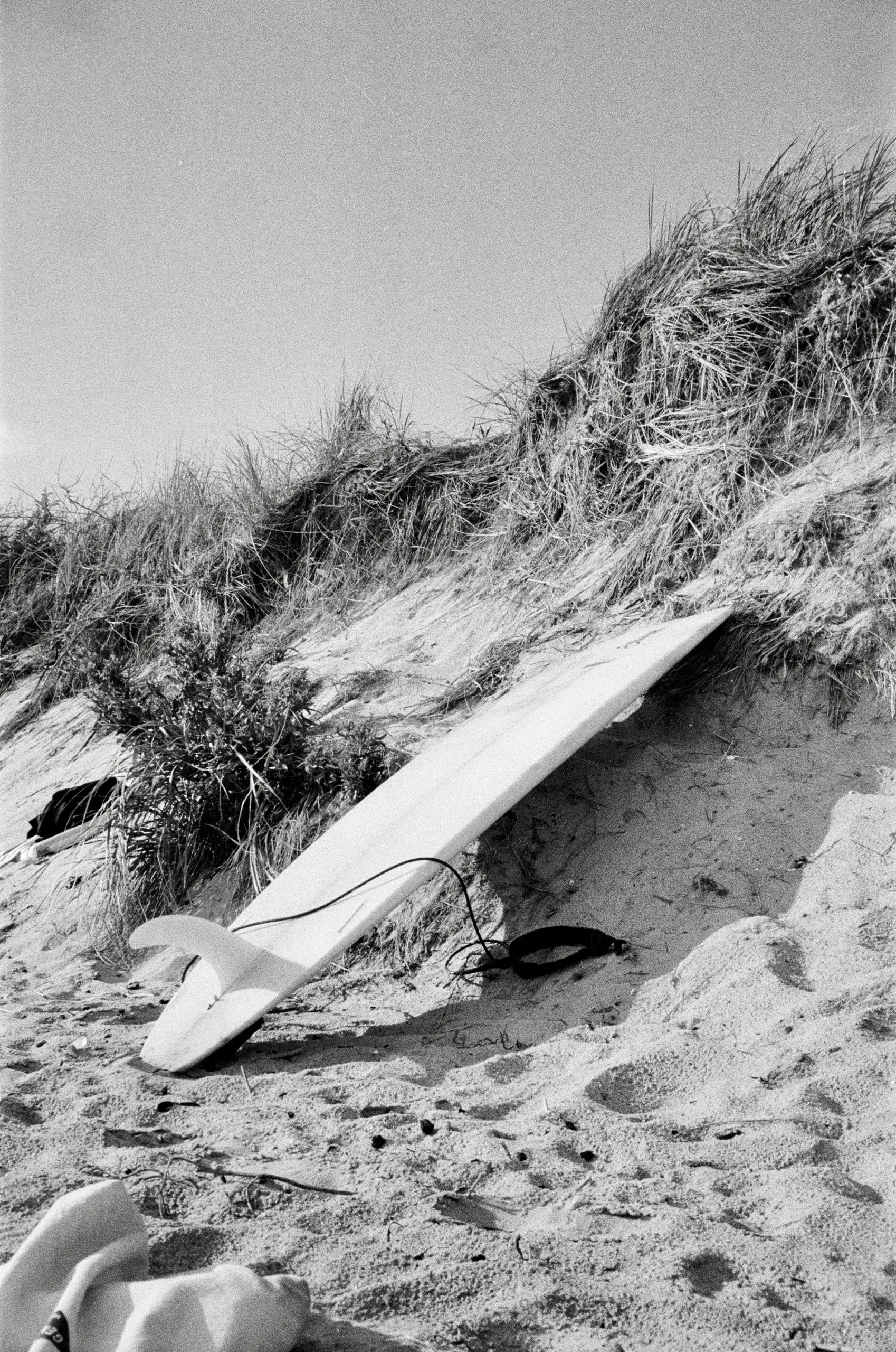 A monochrome photo captures a surf boat lying on the beach.